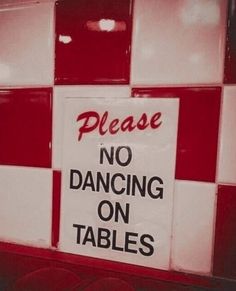 a sign that says please no dancing on tables in front of red and white tiles