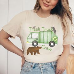 a woman wearing a trash truck crew t - shirt with a brown bear on it