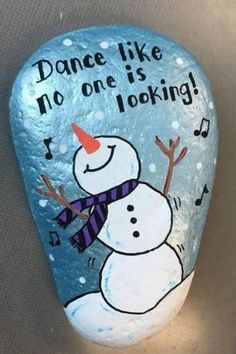 a painted rock with a snowman saying dance like no one is looking