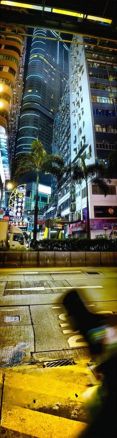 a blurry photo of a city street at night with tall buildings in the background