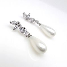 Tarnish resistant white gold plated brass half flower post earrings (posts are sterling silver) decorated with luxury cubic zirconia and high aaa quality off white (pale light cream) teardrop shell pearls. Size:3.8.cm x .8 cm Formal White Pearl Drop Clip-on Earrings, Pear-shaped White Pearl Earrings For Wedding, Elegant White Pearl Drop Clip-on Earrings, White Pearl Shell-shaped Earrings, White Pearl Drop Shell-shaped Earrings, Wedding Gifts For Bridesmaids, Pearl Cream, Zirconia Earrings, Cubic Zirconia Earrings