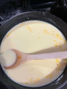 a wooden spoon in a pan filled with milk and orange zest on the stove