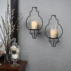 two glass candle holders are on the wall