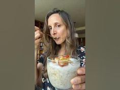 a woman holding a glass filled with food