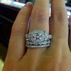 a woman's hand with two engagement rings on top of her wedding band and an engagement ring in the middle