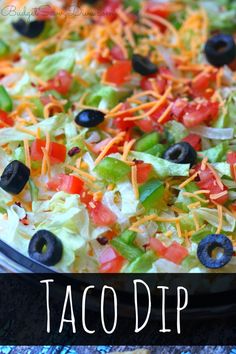 this taco dip is loaded with cheese, black olives and lettuce