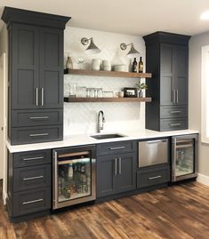 a kitchen with dark gray cabinets and white counter tops, wood flooring and open shelving