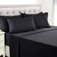 a bed with black sheets and pillows on it