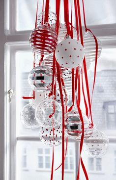 a bunch of ornaments hanging from the side of a window with red and white ribbons