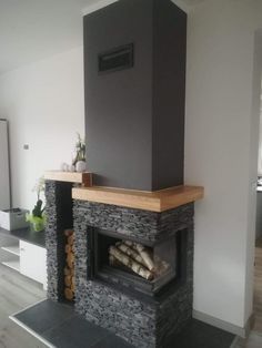 a living room with a fire place in the center and wood logs on the floor