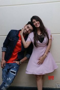 a man and woman are posing for a picture in front of a wall with their arms around each other