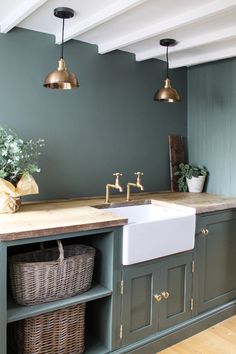 a kitchen with green painted walls and gold faucets on the sink countertop