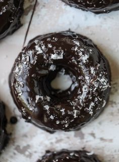 chocolate covered doughnuts sitting on top of a white countertop next to each other