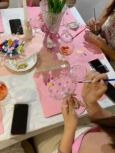 two women are sitting at a table with pink napkins and flowers in vases