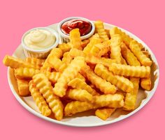 french fries with ketchup and mayonnaise on a white plate against a pink background