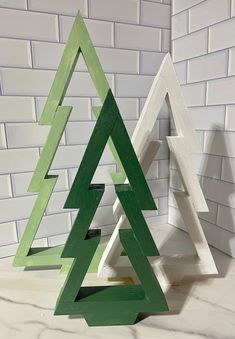 two wooden christmas trees sitting next to each other on top of a white tile floor