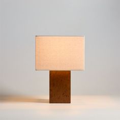 a lamp that is on top of a wooden block with a white shade over it