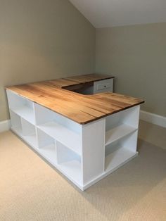 an empty room with a wooden counter top in the center and shelving unit below