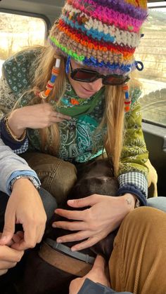 a woman sitting in the back seat of a car petting a dog with her hands