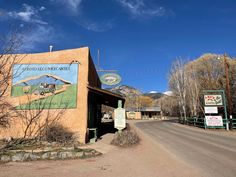 the entrance to an old western town with a sign on it's side and mountains in the background