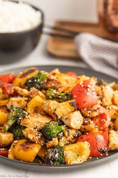 a black plate topped with chicken and veggies