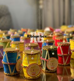 colorful drum shaped boxes are sitting on a table with ribbons around them and the words ribbon box