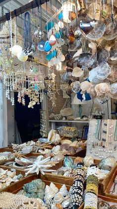 an assortment of jewelry and necklaces in a market stall with lots of them hanging from the ceiling