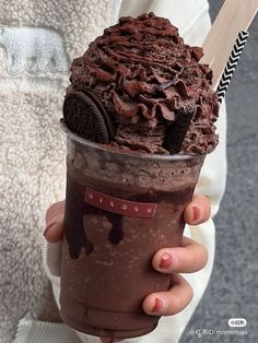 a person holding up a chocolate ice cream sundae