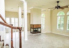 an empty living room with two windows and a ceiling fan