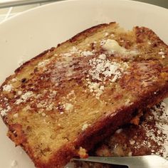 two slices of toast with powdered sugar on them and a fork in the bowl