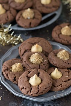 chocolate cookies with white frosting and gold sprinkles are on a plate