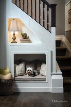 a dog is sitting in his bed under the stair case at the bottom of the stairs