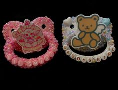 two hello kitty brooches are sitting next to each other on a black surface