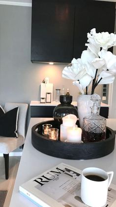 a tray with flowers and candles on top of a table in a living room next to a chair