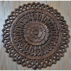 an intricately carved wooden wall hanging on a wood floor with circles and spirals in the center