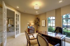 a home office with two chairs and a desk in front of large windows that look out onto the yard