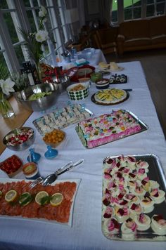 a table topped with lots of food on top of a white tablecloth covered table