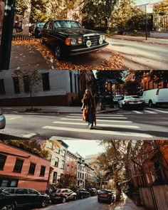 a woman walking across a street next to tall buildings and parked cars on the side of the road