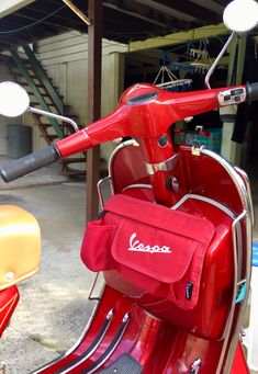 a red scooter parked in front of a garage