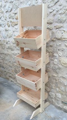 an unfinished wooden shelf with drawers on it in front of a stone wall and cement floor