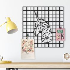 a wooden desk topped with a computer monitor next to a wall mounted art work piece