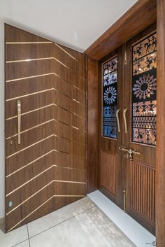 an entry way with wooden doors and decorative panels on the side wall, along with tile flooring