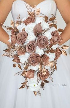 a bridal holding a bouquet of white and pink flowers with gold leaves on it