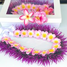 purple and yellow flowers are placed in front of a white box