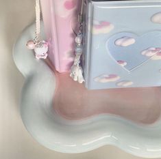 a pink and blue suitcase sitting on top of a white cloud shaped shelf next to other items