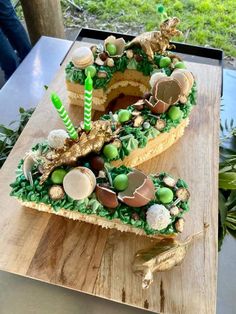 a cake shaped like the letter s on top of a wooden table with green decorations