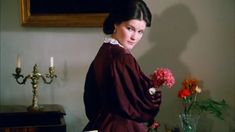 a woman standing next to a vase with flowers in it