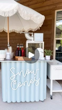 an ice cream stand with white umbrellas on it's roof and the words snow cones written in cursive writing