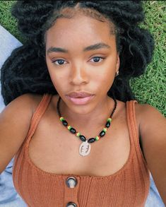 a woman laying in the grass wearing a necklace