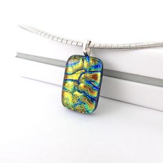 This unique petite dichroic glass pendant has immense depth of colours finished with a clear glass and hand polished to smooth.  Featuring yellow golden glass with veins of cobalt blue, and lime green it is a real stunner that slightly changes colour depending on the angle of light. This pendant is approximately 1 inch long, mounted on a silver plated bail. It will arrive wrapped in tissue paper inside a small gift ouch.  A lovely one of a kind gift for someone special. **This is a pendant only, chain is not included. More original dichroic glass pieces: https://www.etsy.com/uk/shop/LeanneStreet?ref=seller-platform-mcnav Modern Rectangular Glass Jewelry, Modern Murano Glass Jewelry Gift, Modern Murano Glass Jewelry As Gift, Handmade Pendant Necklace, Dichroic Glass Pendant, Fused Glass Jewelry, Glass Pieces, Dichroic Glass, Handmade Pendant